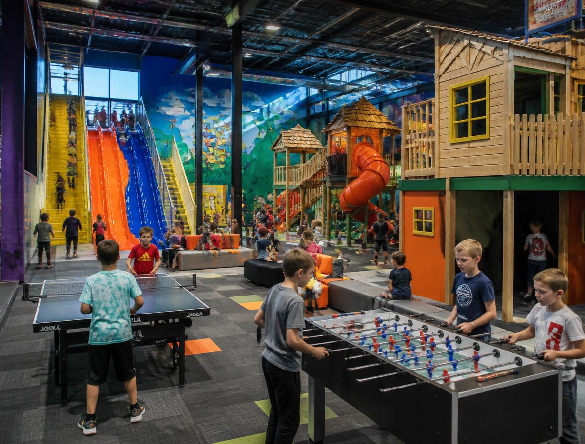 Big kids zone with tall slides, wooden playhouses, foosball and ping pong tables
